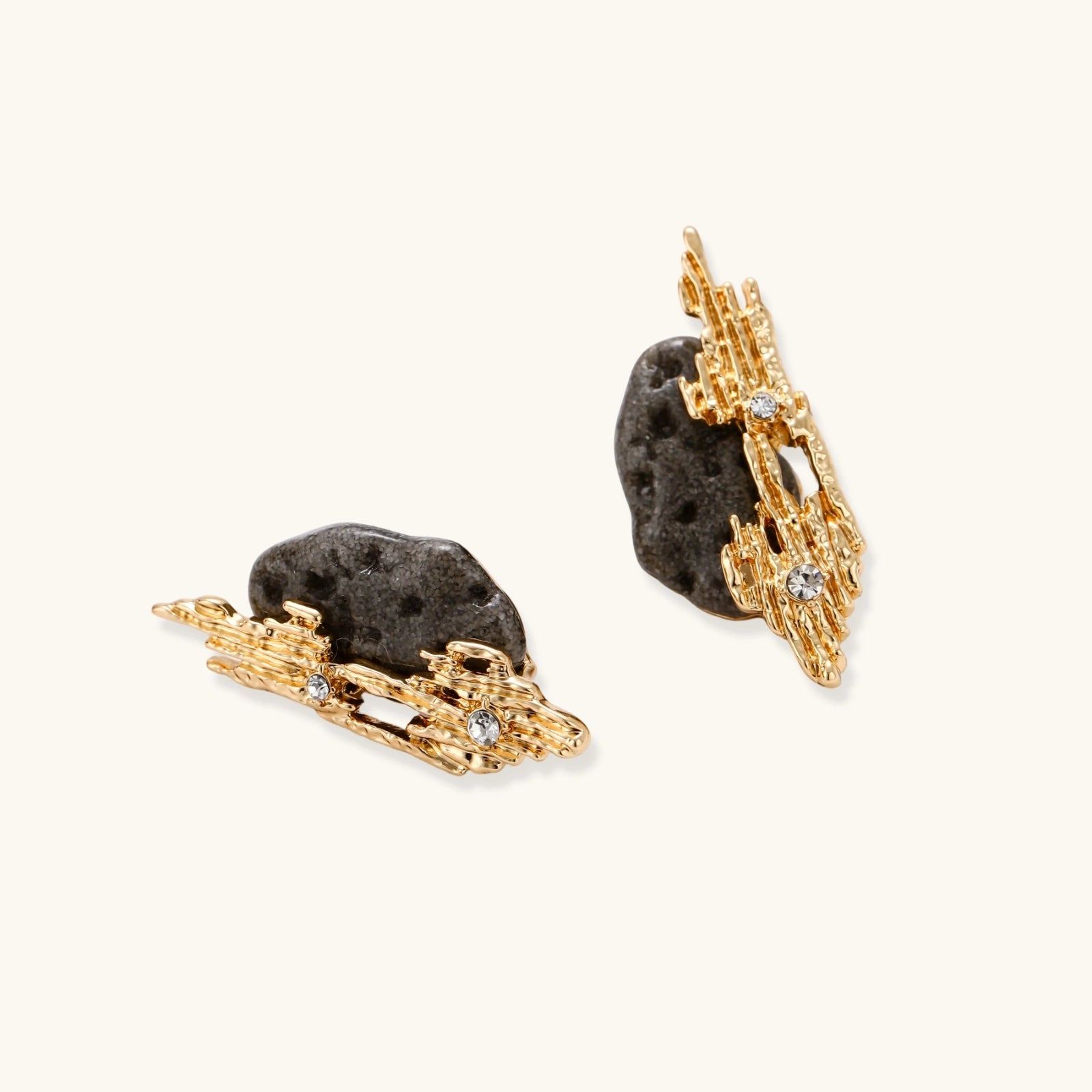 Sculptural statement earrings with textured volcanic stones and flowing silver metal design with crystal accents