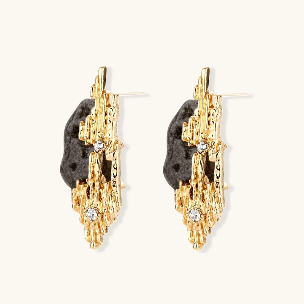 Sculptural statement earrings with textured volcanic stones and flowing silver metal design with crystal accents